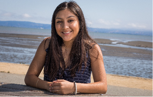 Smiling female undocumented student with mountains and ocean in background (DREAMers, Annual Letter, CZI).