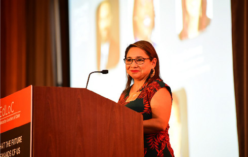 Woman in glasses at podium, speaking at a greater diversity in education leadership conference (Education Leaders of Color, Annual Letter, CZI).