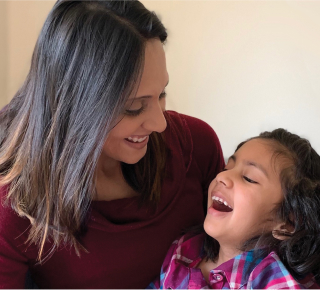 INADcure Foundation president and co-founder holding her young daughter, who has the rare disease Infantile Neuroaxonal Dystrophy, as both smile.