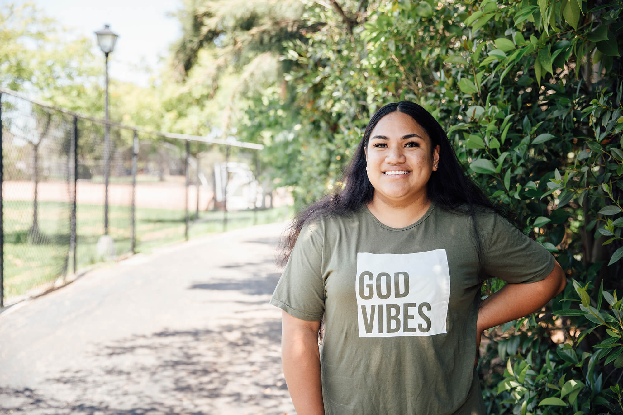 A woman smiles and wears a green shirt that says "God Vibes."