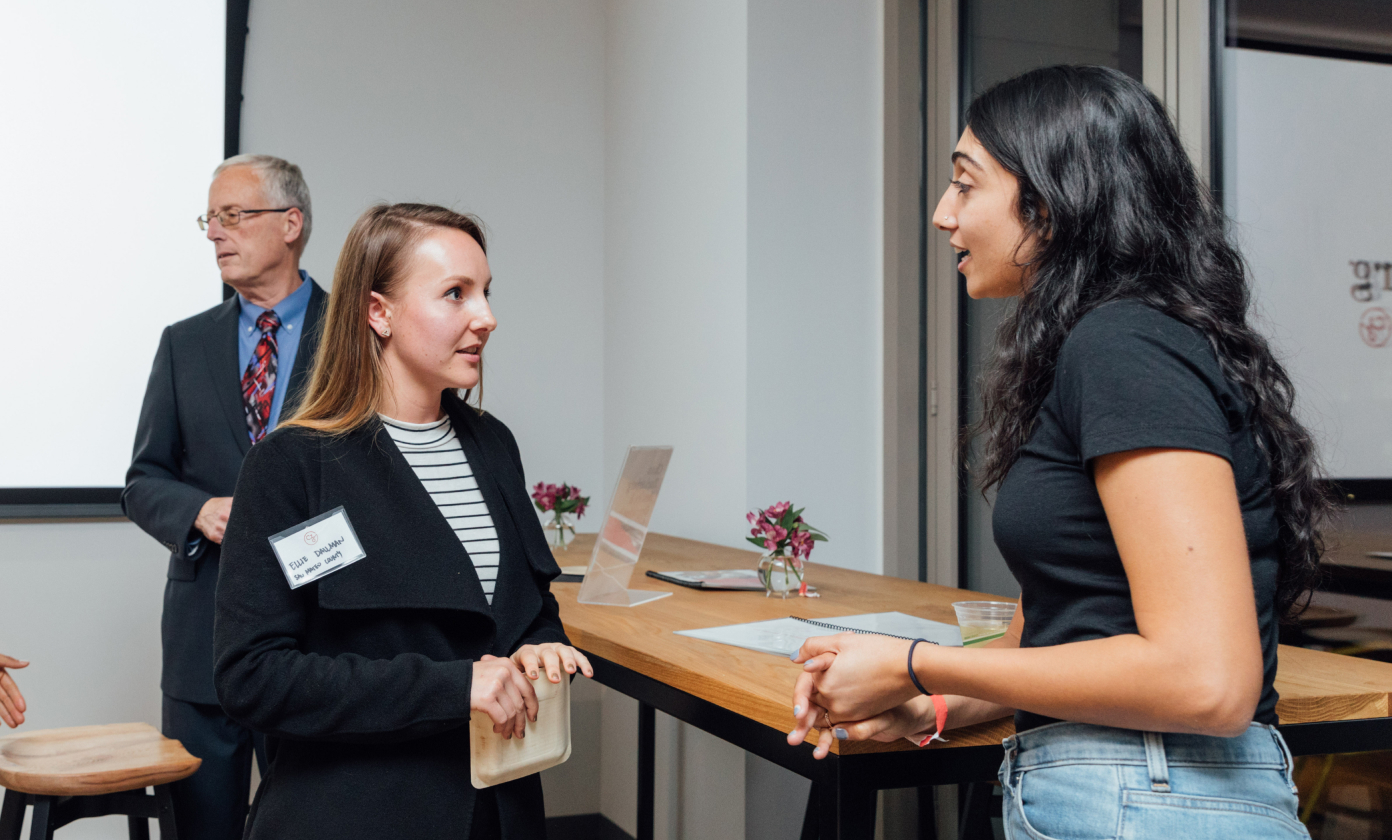 Ruby Bolaria Shifrin, Director, Housing Affordability, CZI, speaking with a woman at a community reception in Redwood City, California.
