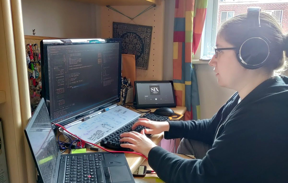 A women wears headphones and works at a computer.