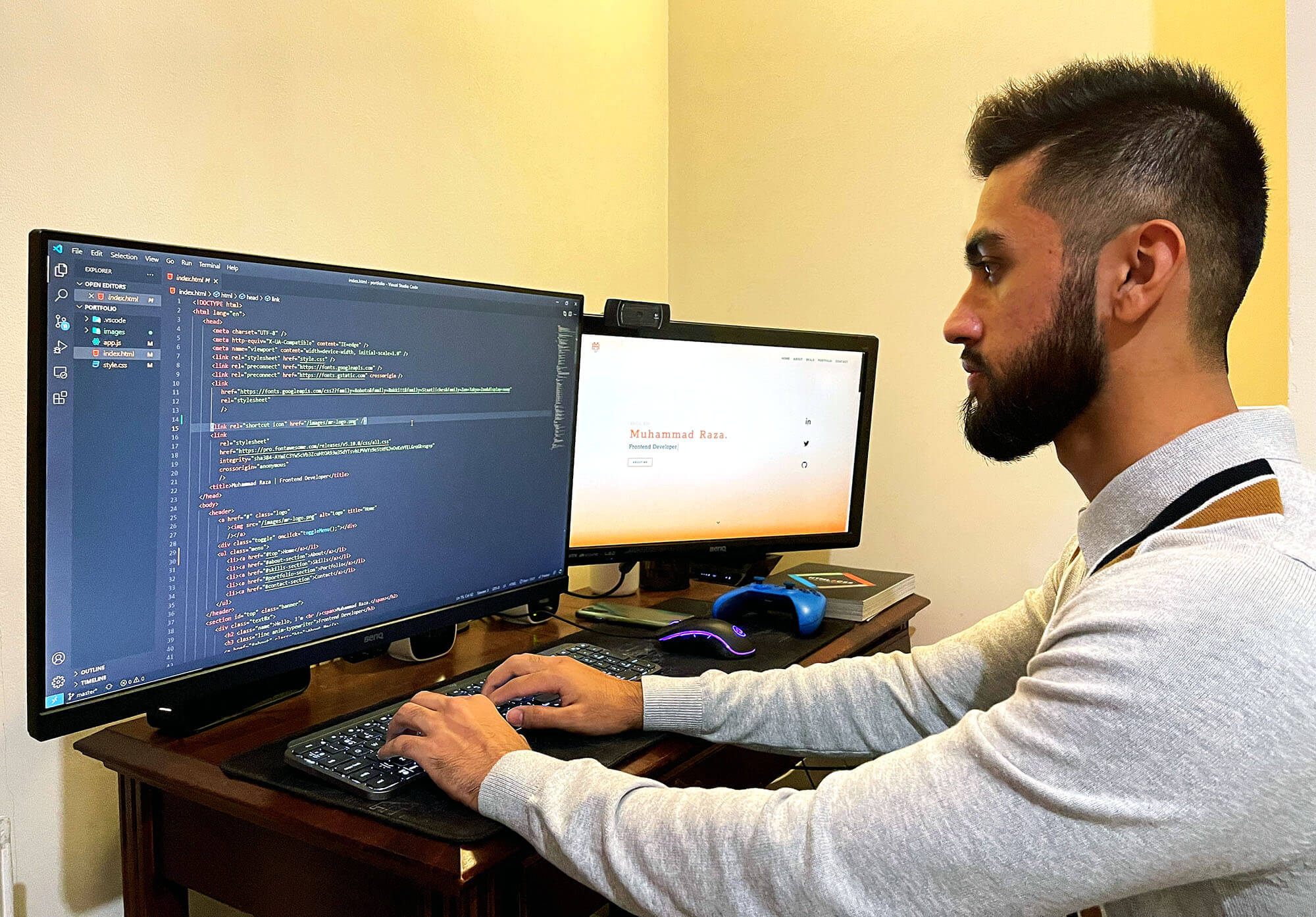 A man work at two computer screens, one of which displays lots of code.