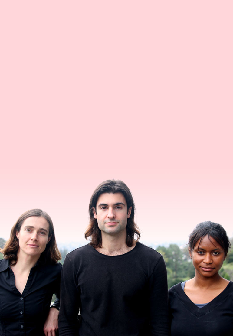 A headshot of three people in black tops on a pink background.