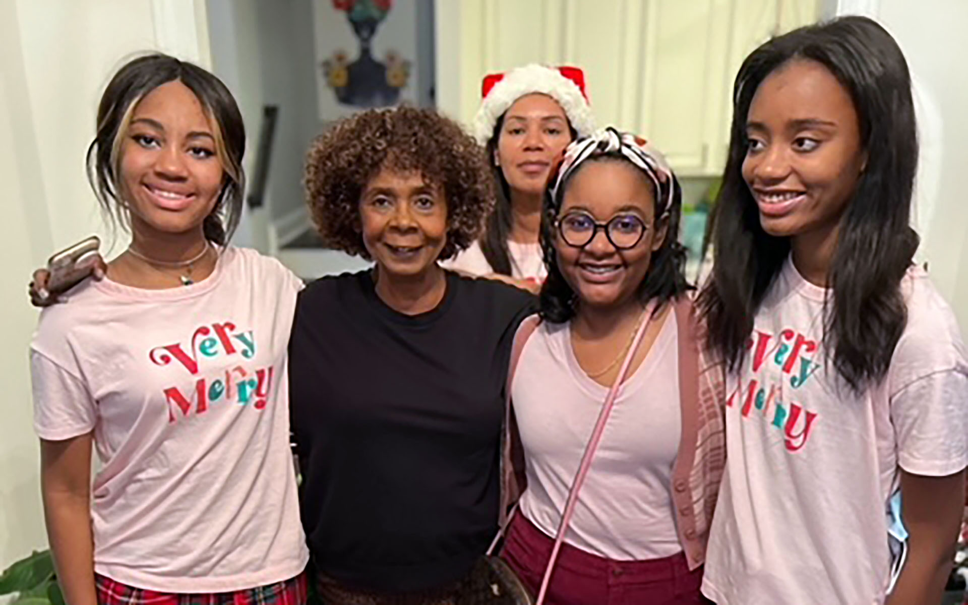 A group of women smiling. One wears a Santa hat and others wear Christmas pajamas.