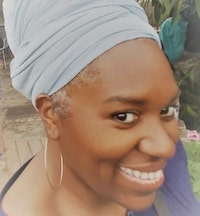 Black woman in a purple blouse wearing a large hoop earring. She is smiling and wearing a teal headwrap.