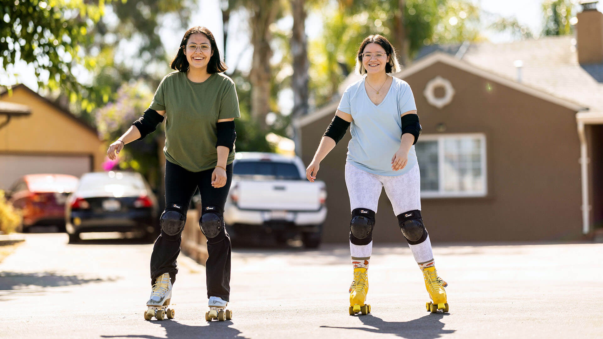 Two women smile while roller skating outside.