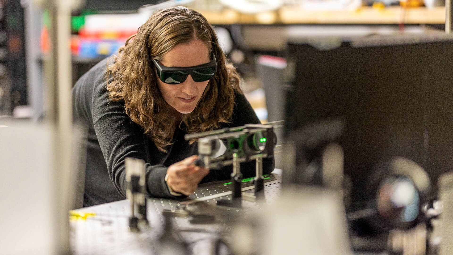 Laura wears dark glasses uses equipment in a computer imaging lab