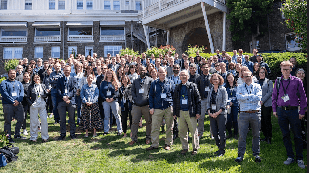 Over 100 scientists gather, smile, and stand together for a group photo outside the Claremont Hotel.