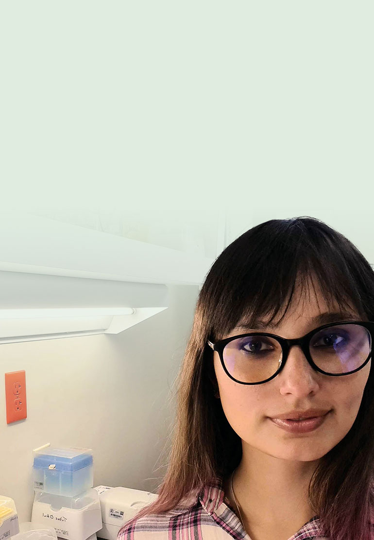 A woman with dark hair and glasses in a lab.
