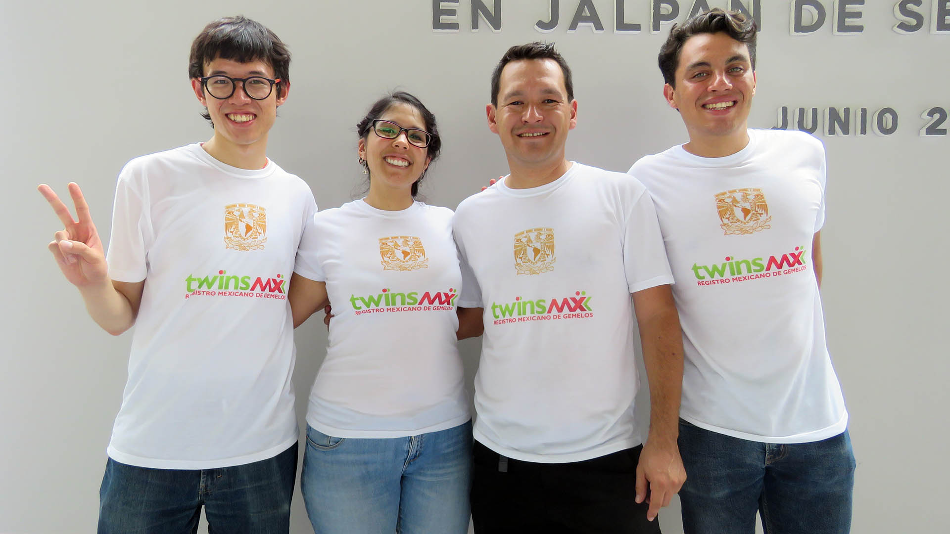 Four people smile wearing white shirts that read “TwinsMX Registro Mexicano de Gemelos.” 