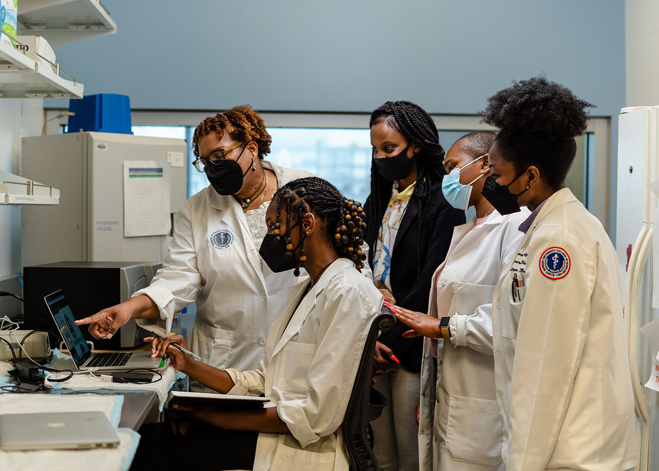A group of scientists in Dr. Marjorie Gondre-Lewis’ lab look at laptop.