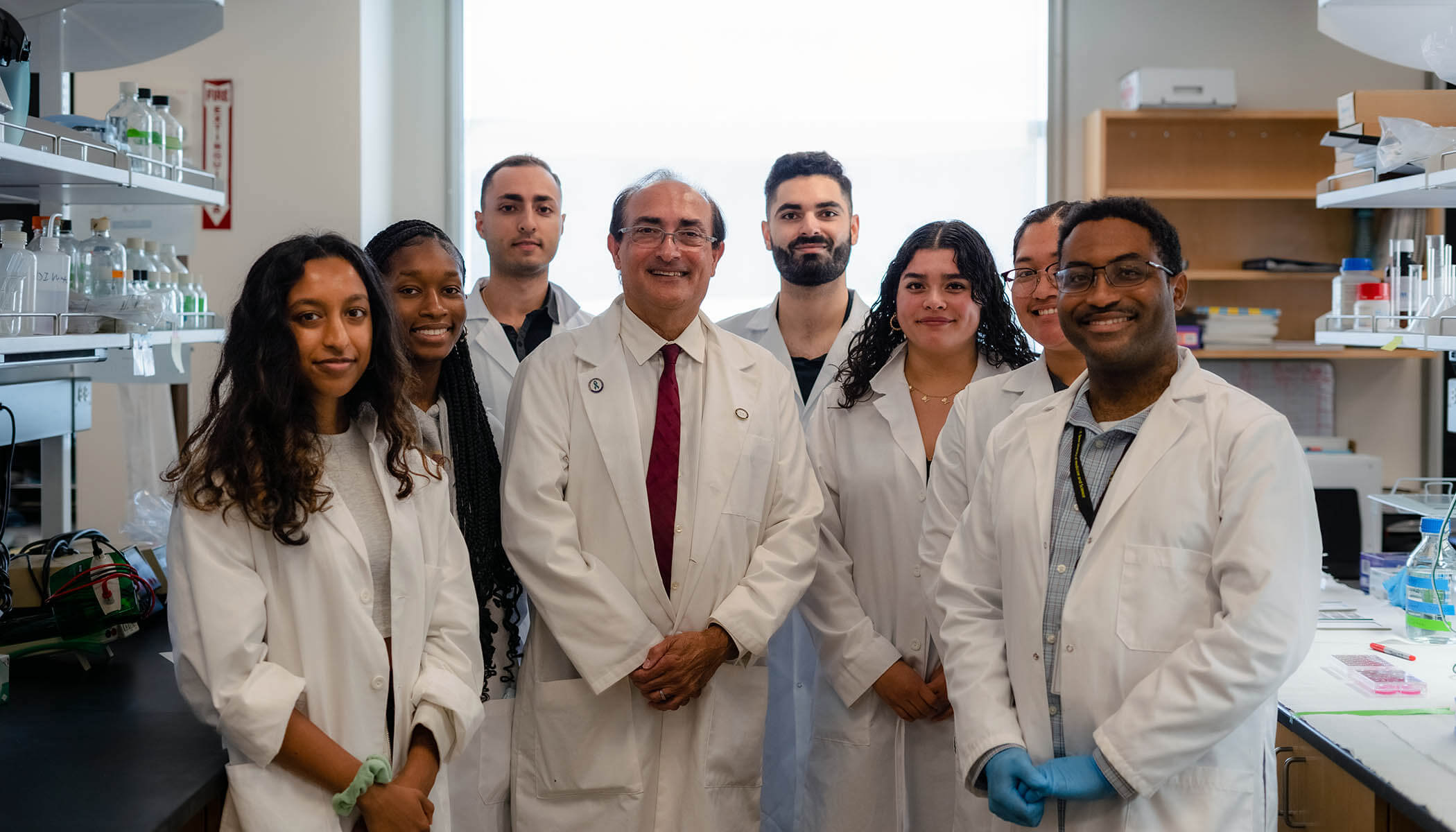 A group of Charles R. Drew University researchers smiles for a photo in a lab.