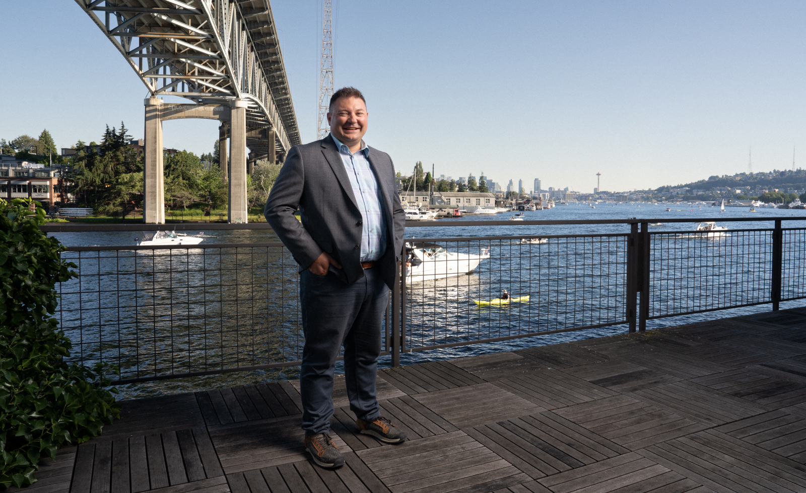 Erik R. Stegman, chief executive officer of Native Americans in Philanthropy, wears a suit and smiles for a photo. A body of water with boats is behind him. 