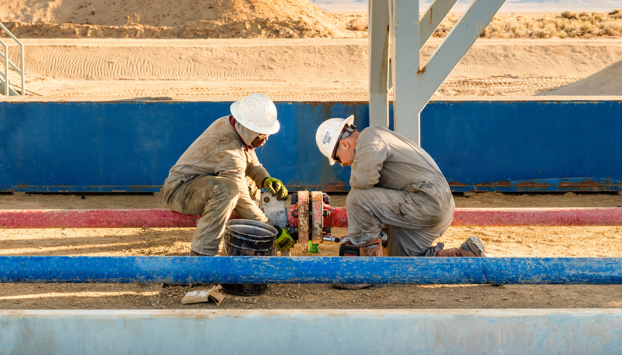 Two workers connecting surface pipes.