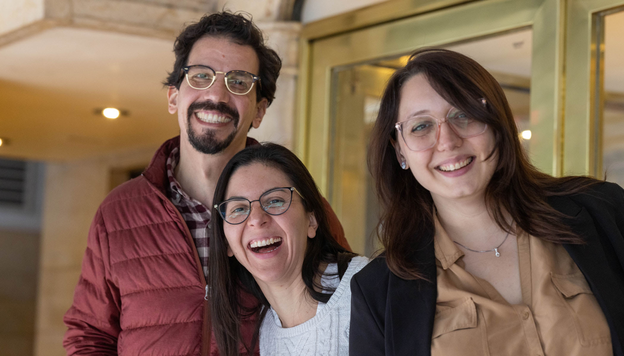 Three people with glasses smile for a group photo at an open science conference.