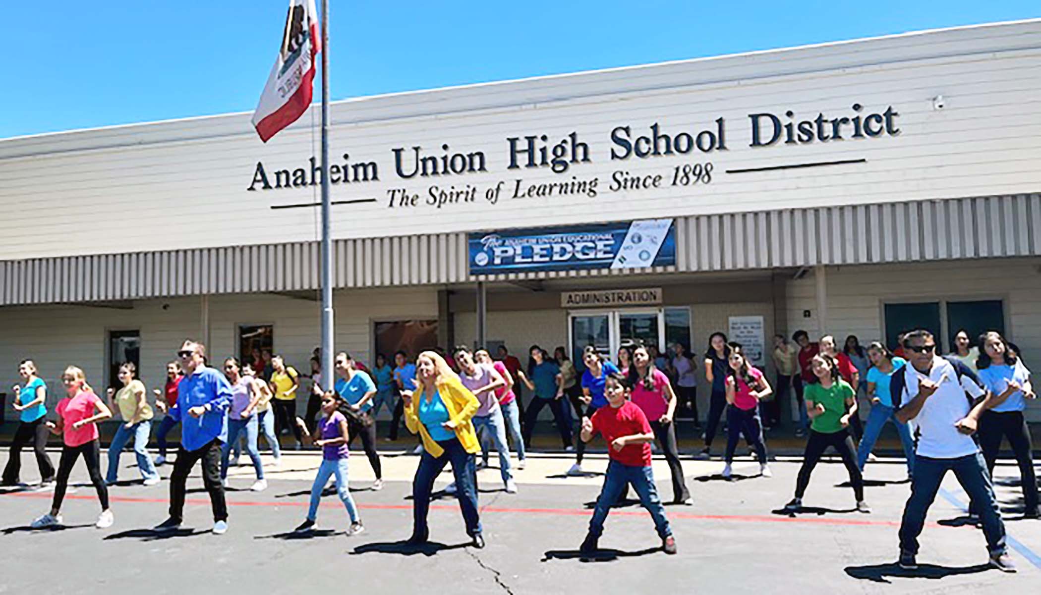 A group of people dances outside of the Anaheim Union High School District building.