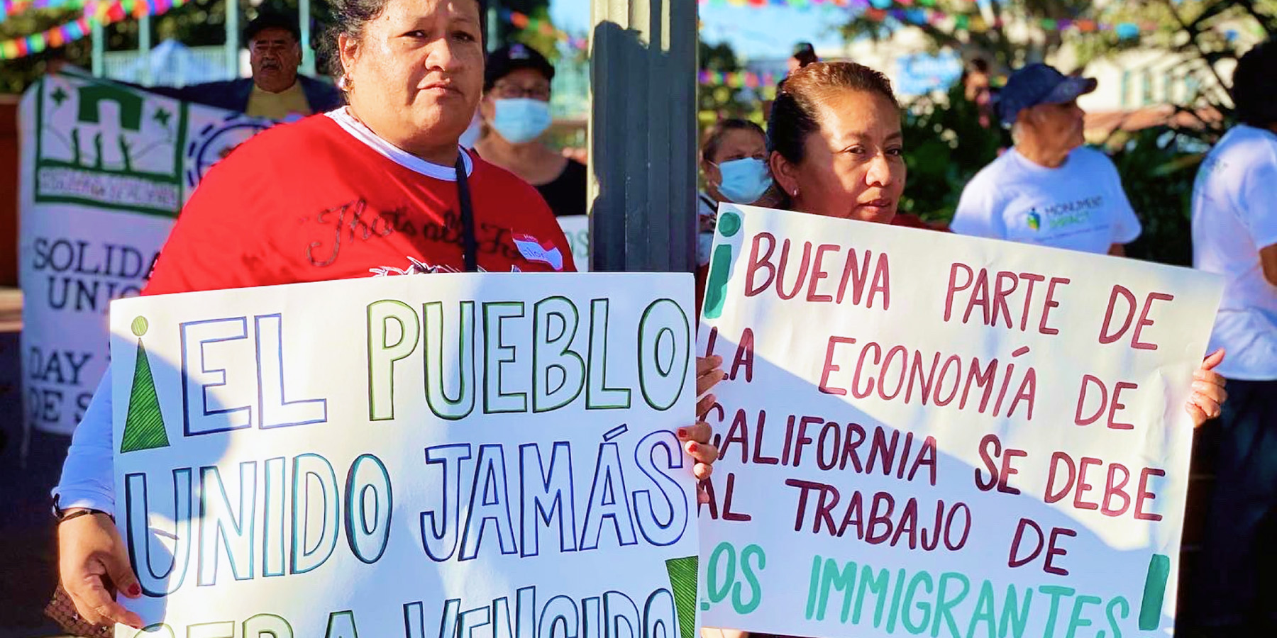 Two people hold signs at a demonstration for immigration rights.