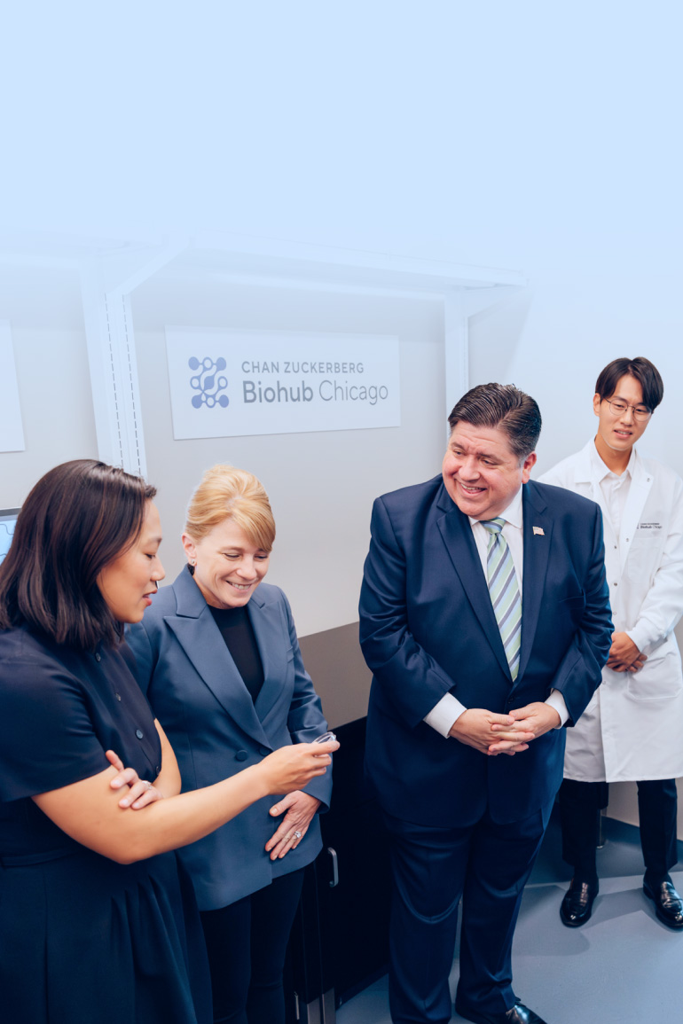 Priscilla Chan, JB Pritzker, and Shana Kelley stand together, looking at a sample in a petri dish.