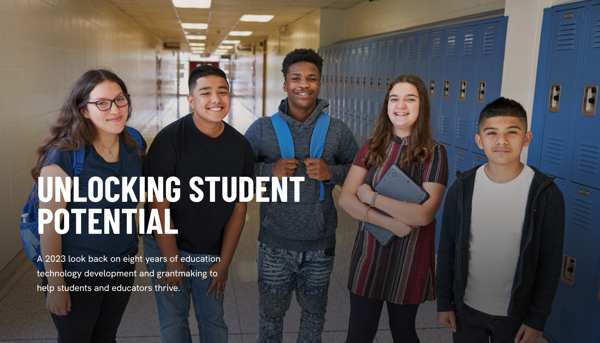 Five teenaged students stand in a school hallway surrounded by lockers.