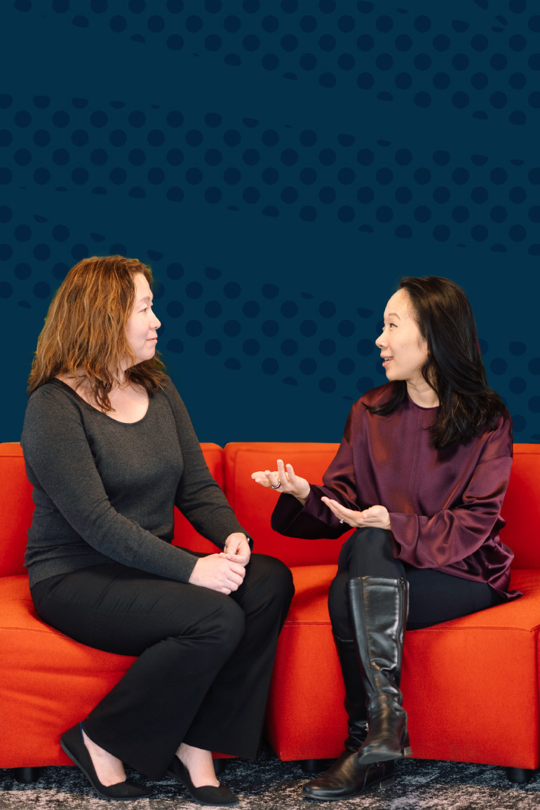 Sandra Liu Huang, CZI’s head of education sits on a red couch and faces Monica Milligan, executive director of Gradient Learning. Both are smiling as they speak.
