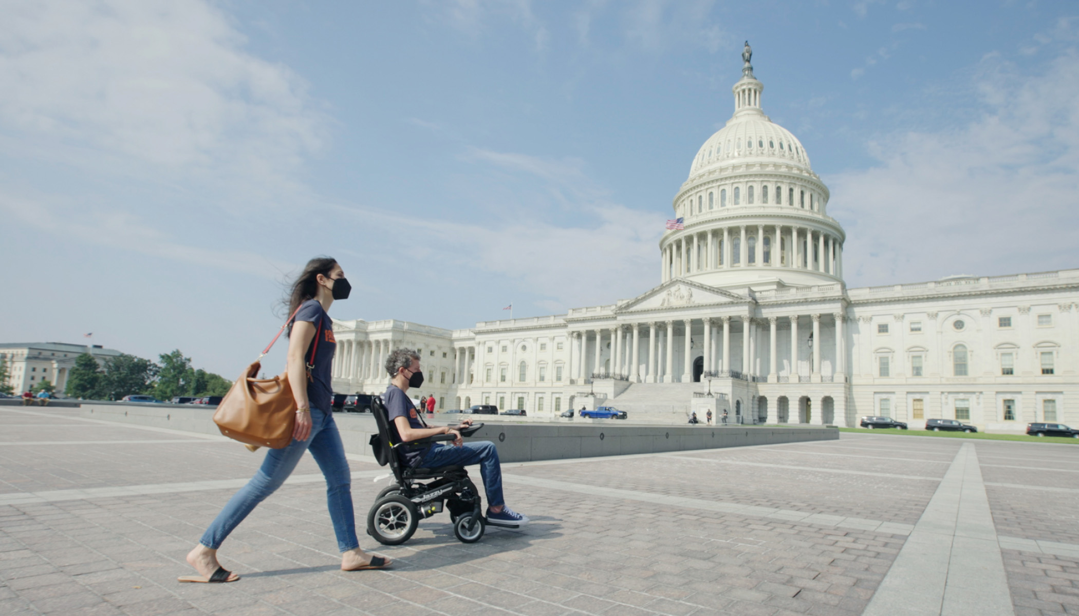 Woman pushing a man in a wheelchair in front of the Capitol Building in Washington, D.C.