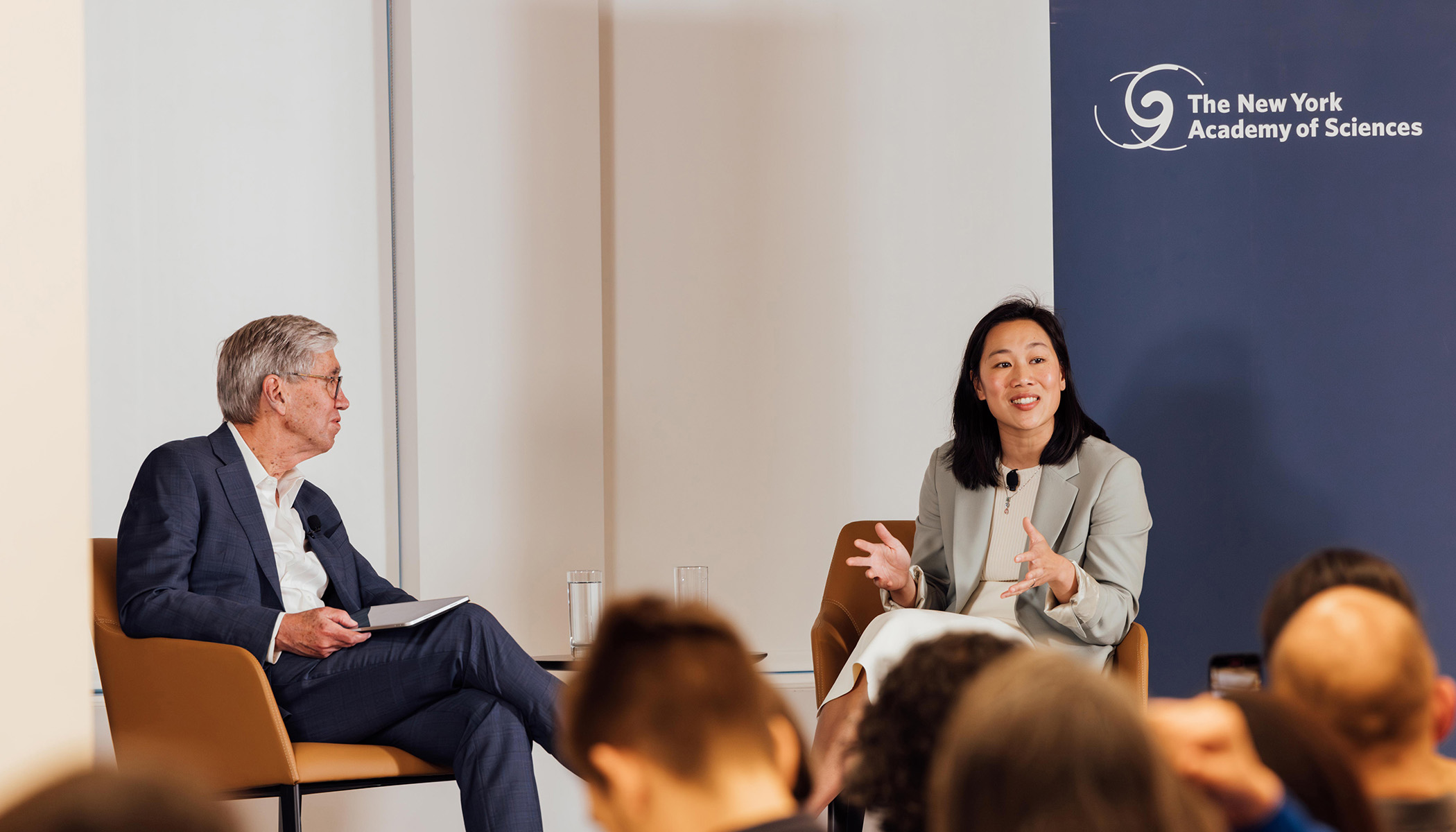 Drs. Richard Lifton and Priscilla Chan sit side-by-side in armchairs on stage.
