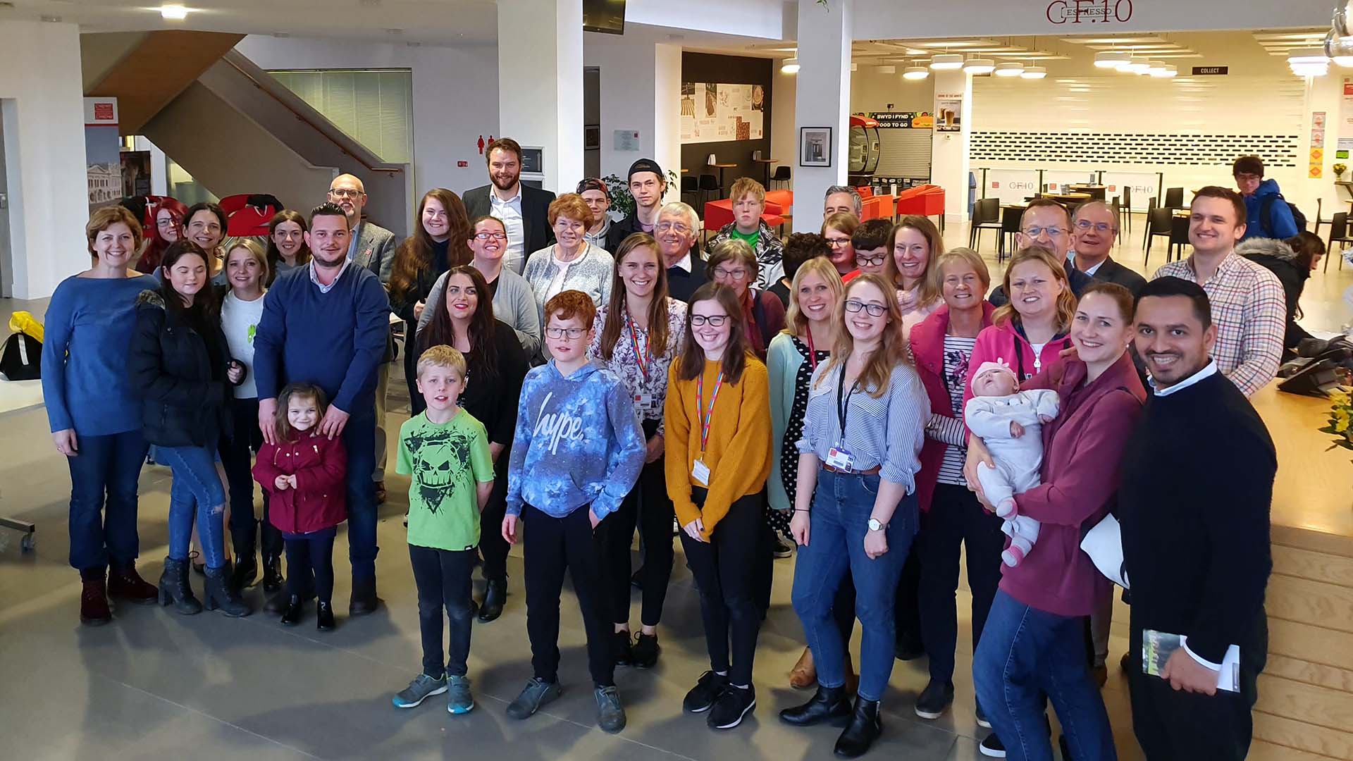 A group of families and researchers, including children and adults, pose indoors.