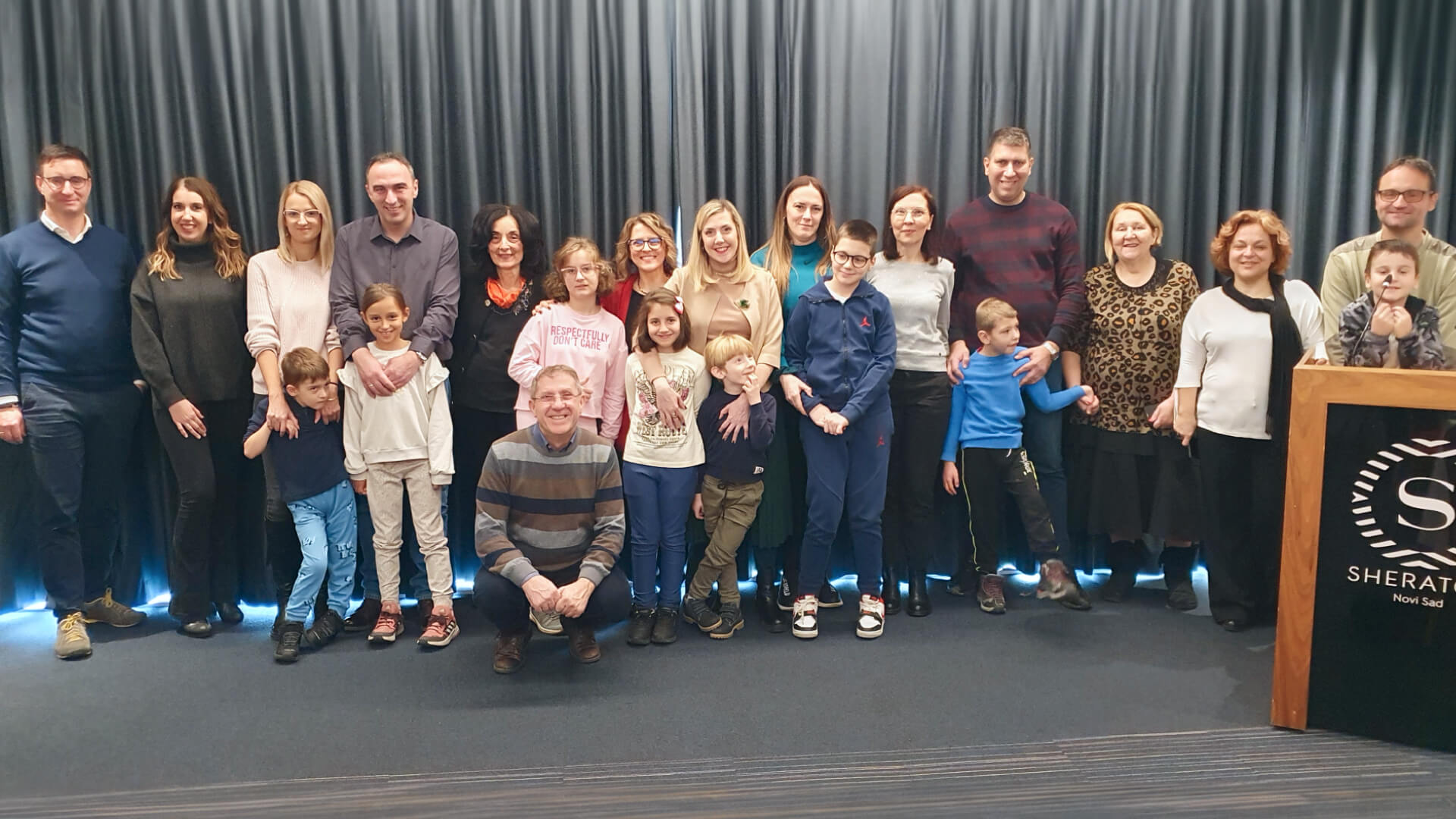 A group of families and healthcare providers, including children and adults, pose indoors.