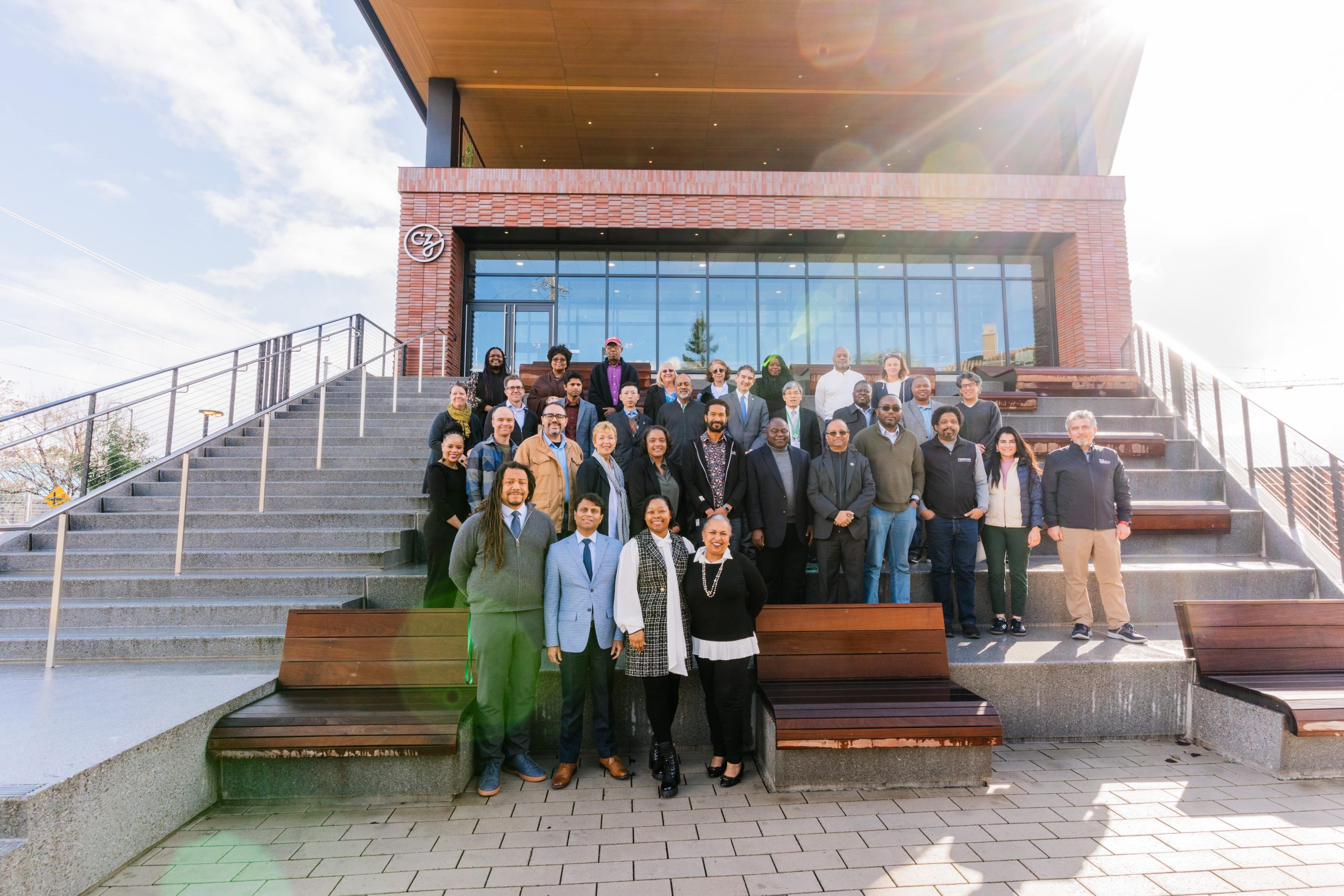 Accelerate Precision Health Grantee Meeting participants stand on the CZI Headquarter steps and pose for a group picture on a sunny morning.