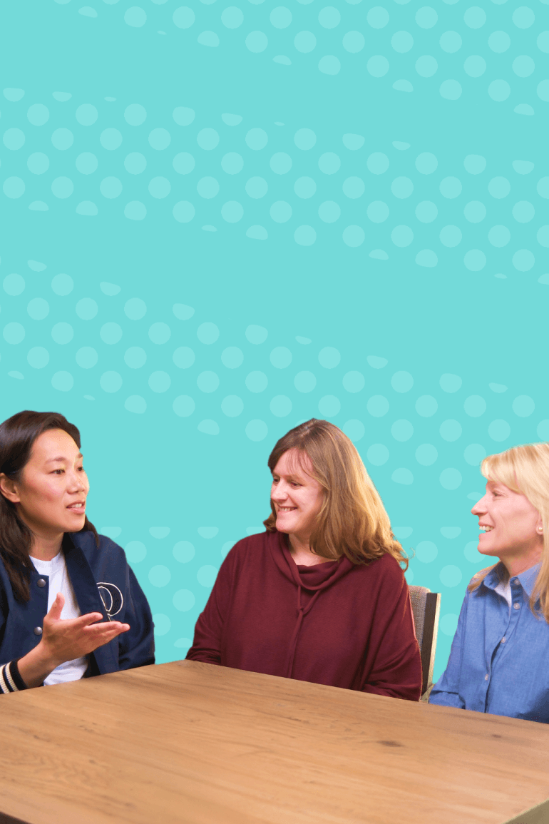 Priscilla Chan engaging in a discussion with Patricia Brennan and Shana Kelley at a table, against a blue background.