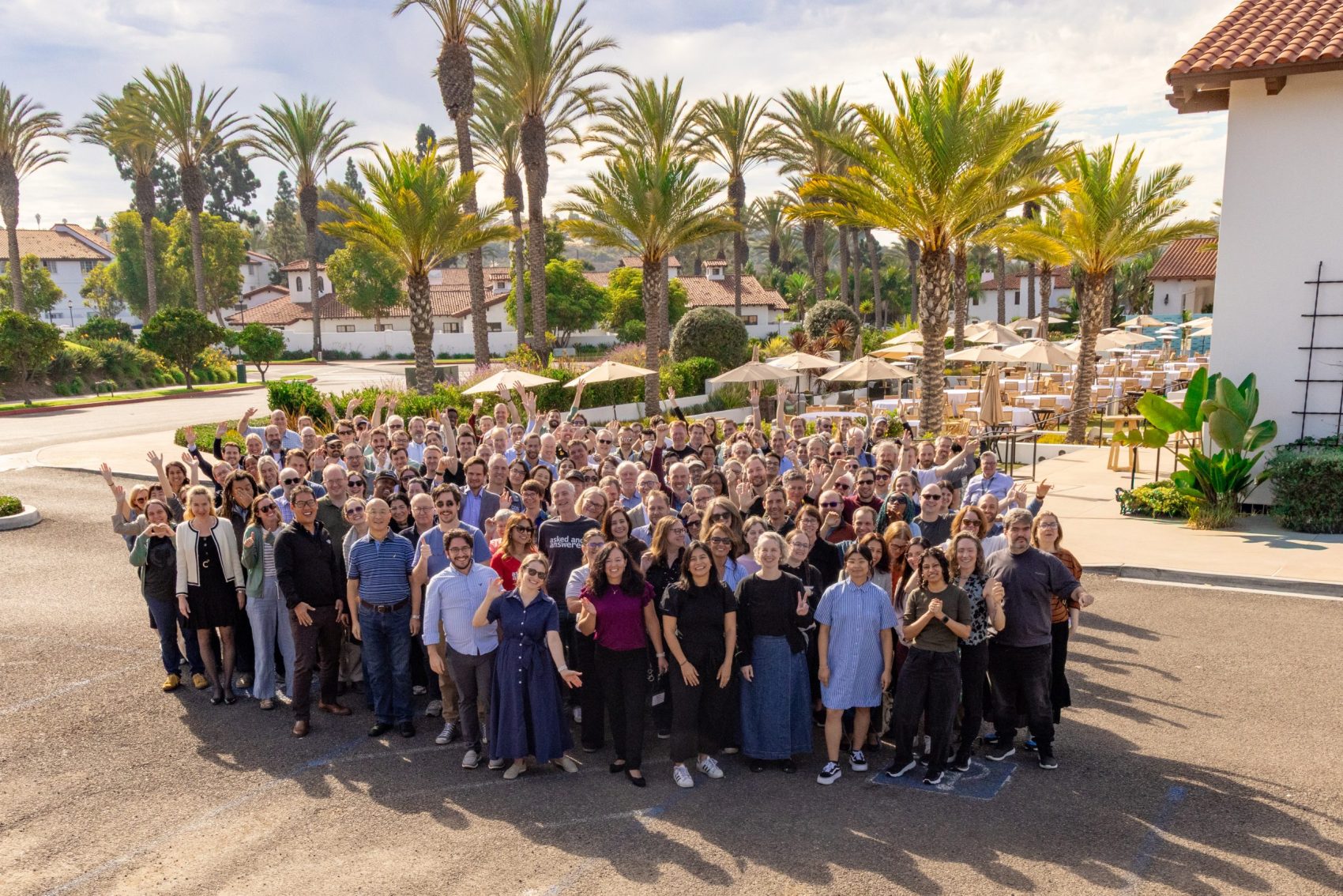 Participants of the CZI Open Science 2025 Meeting smile and wave to the camera near the Luna Lawn of the Omni La Costa Resort & Spa in Carlsbad, CA.