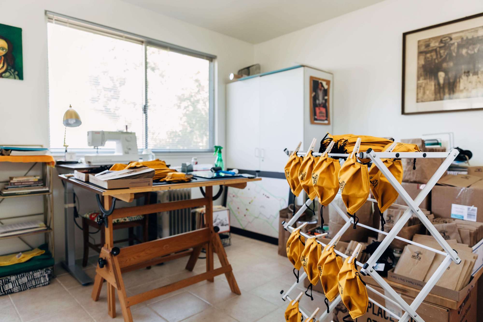 Yellow masks dry on a rack in a workroom.