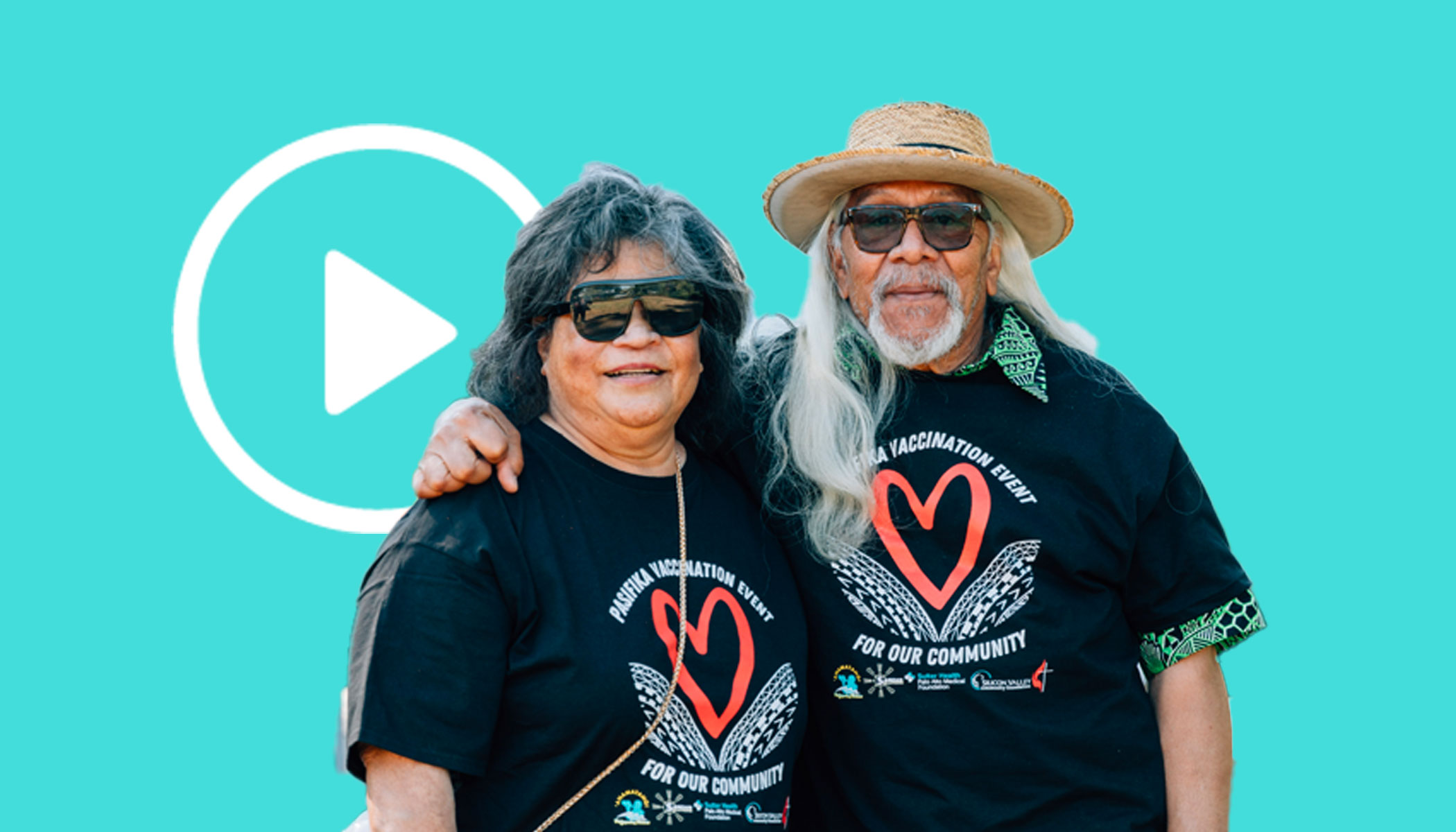 A man and a women pose together. Both are wearing black shirts with red hearts printed on them.