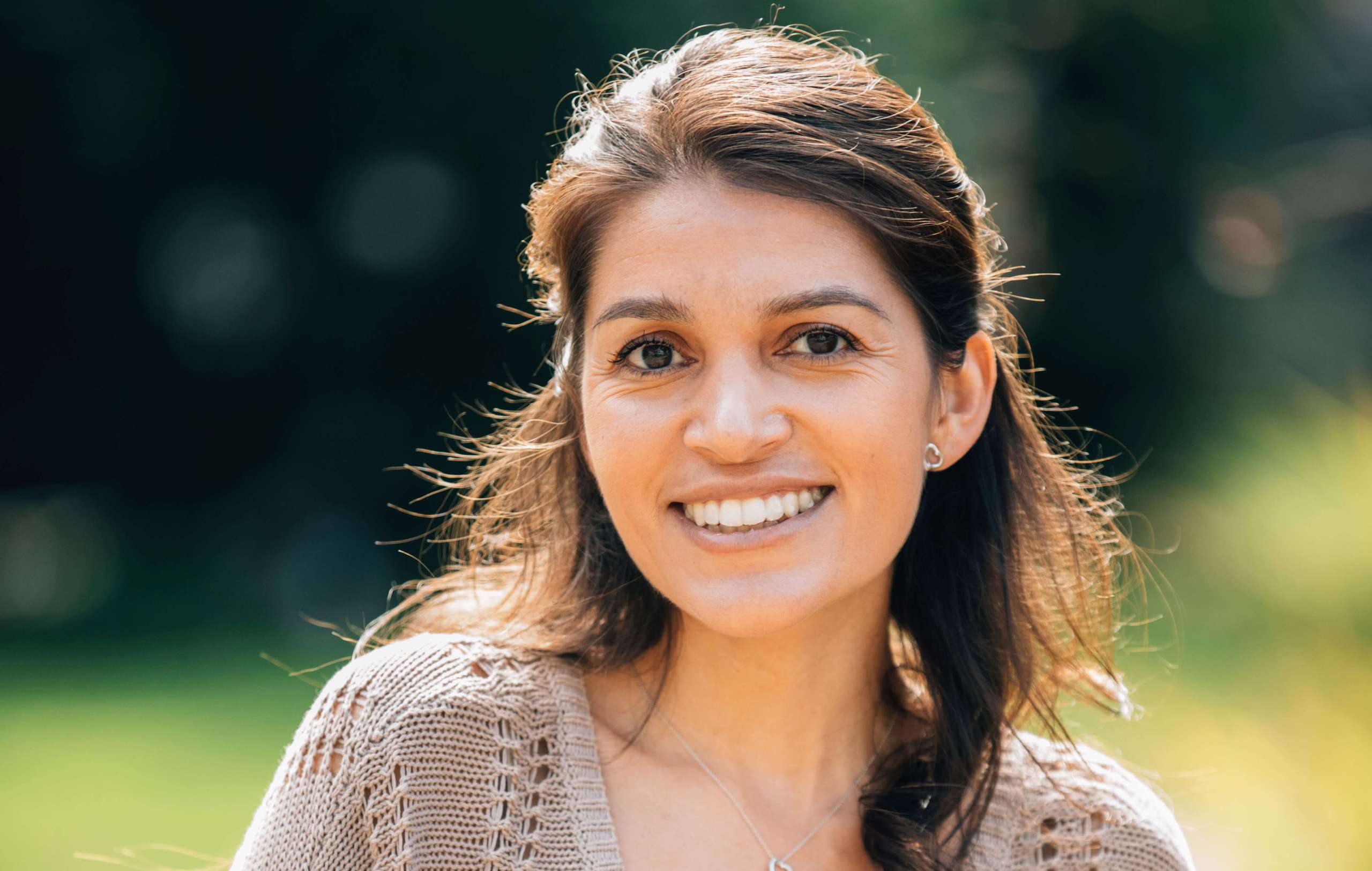 A headshot of a woman smiling, wearing a tan blouse.