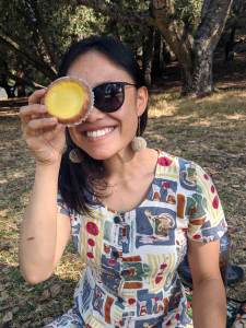 CZI housing affordability manager Michelle smiles and holds a pastry to her eye.