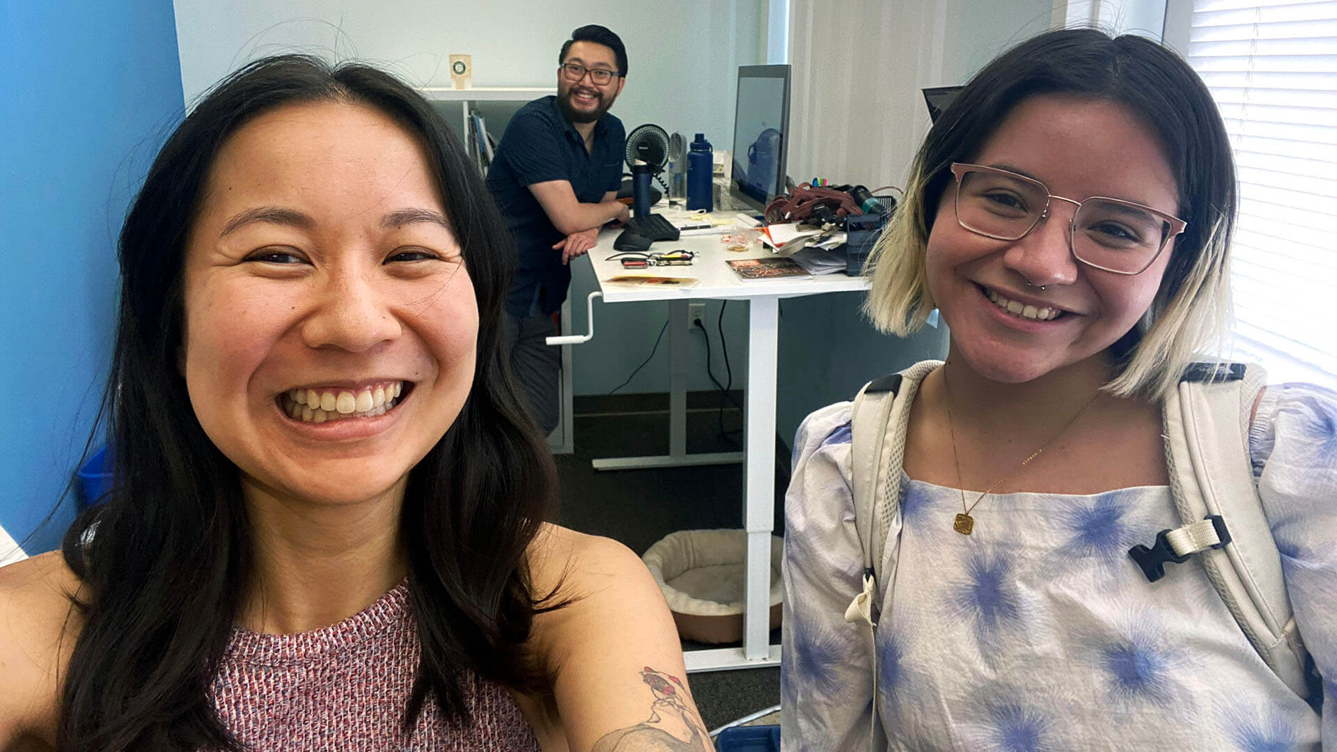Three coworkers smile while in the office.