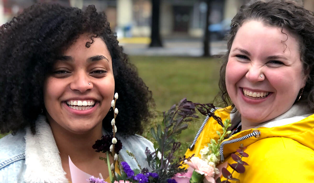 Kindra and her wife smiling and holding a bouquet of flowers.