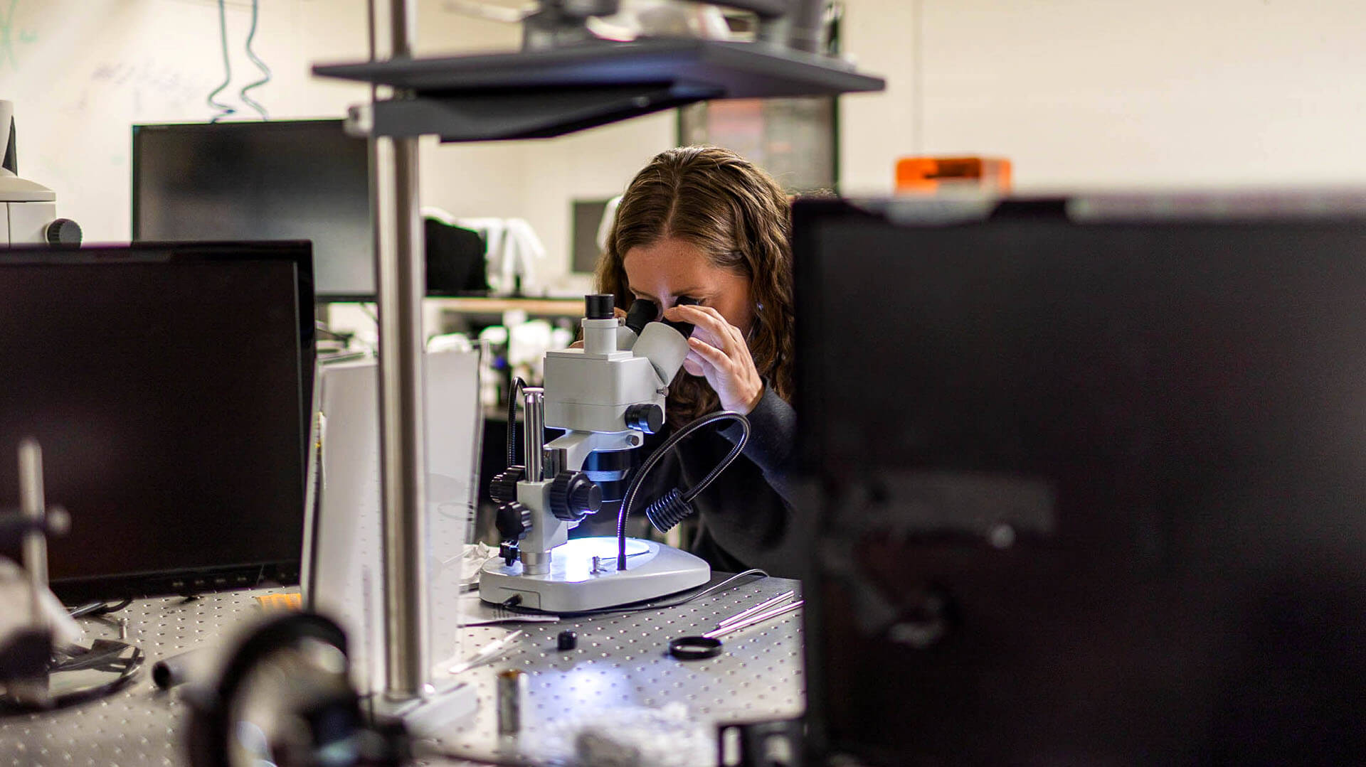 Laura in a computational imaging lab looks through a microscope lens
