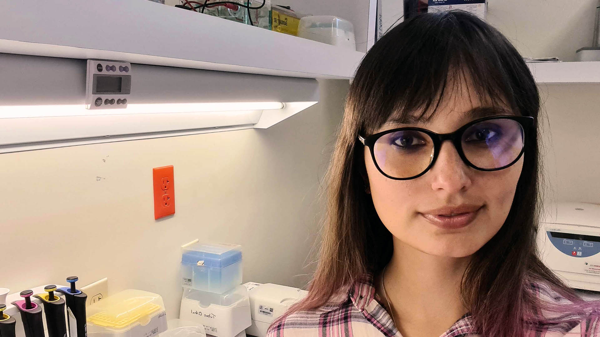 A woman with dark hair and glasses in a lab.