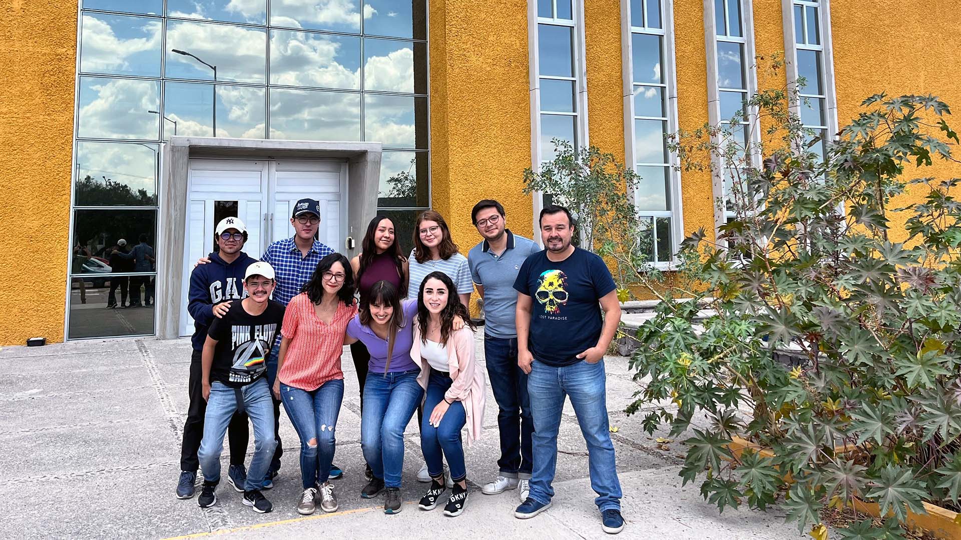 A group of colleagues smile for a photo in front of the International Laboratory for Human Genome Research.