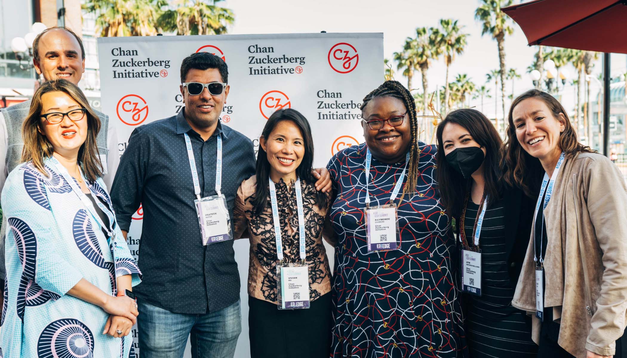 Vivian Wu smiles standing between six colleagues in front of a sign printed with the CZI logo.