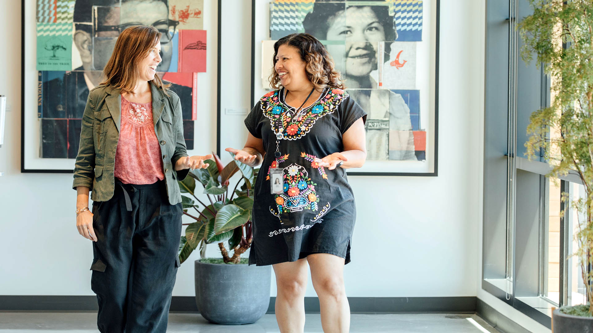 Rosa Cabrera smiles while walking and talking to someone in a hallway of CZI headquarters.
