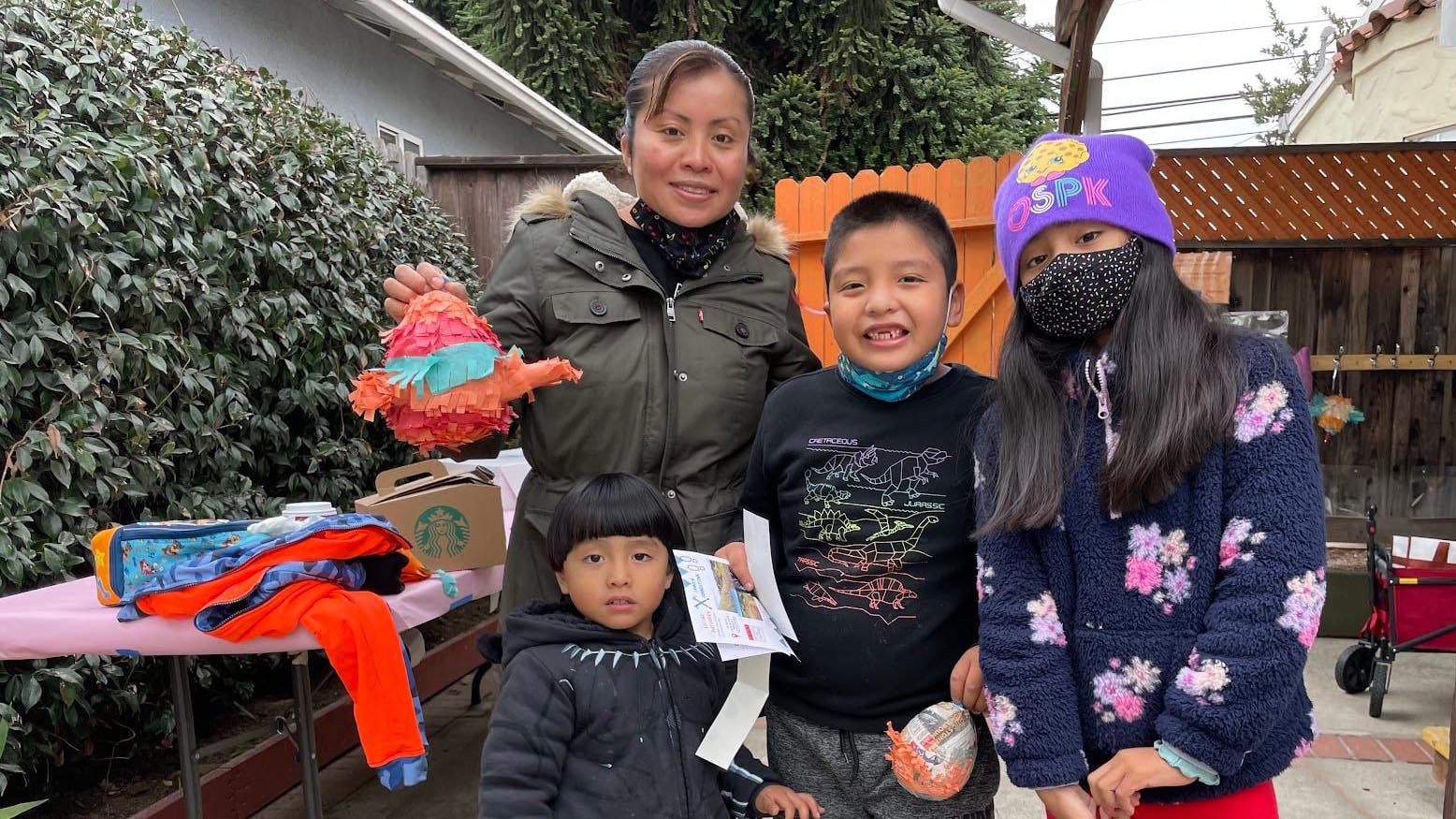 An adult and three children pose for a group photo outside at a Family Connection event.