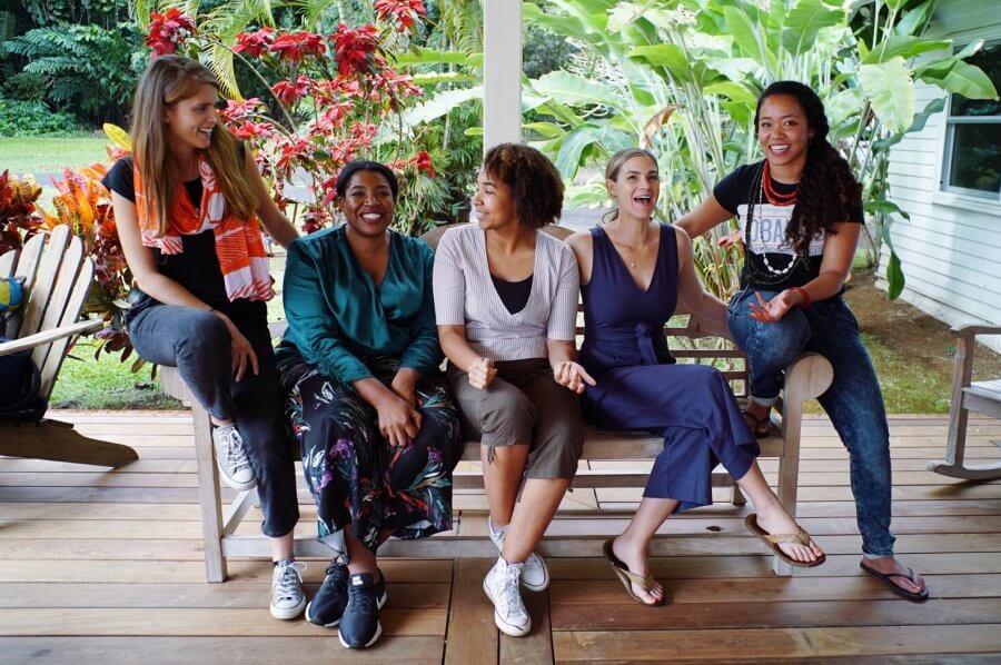 A group of Elemental Execeleator team members smile and chat while sitting on a bench outside.