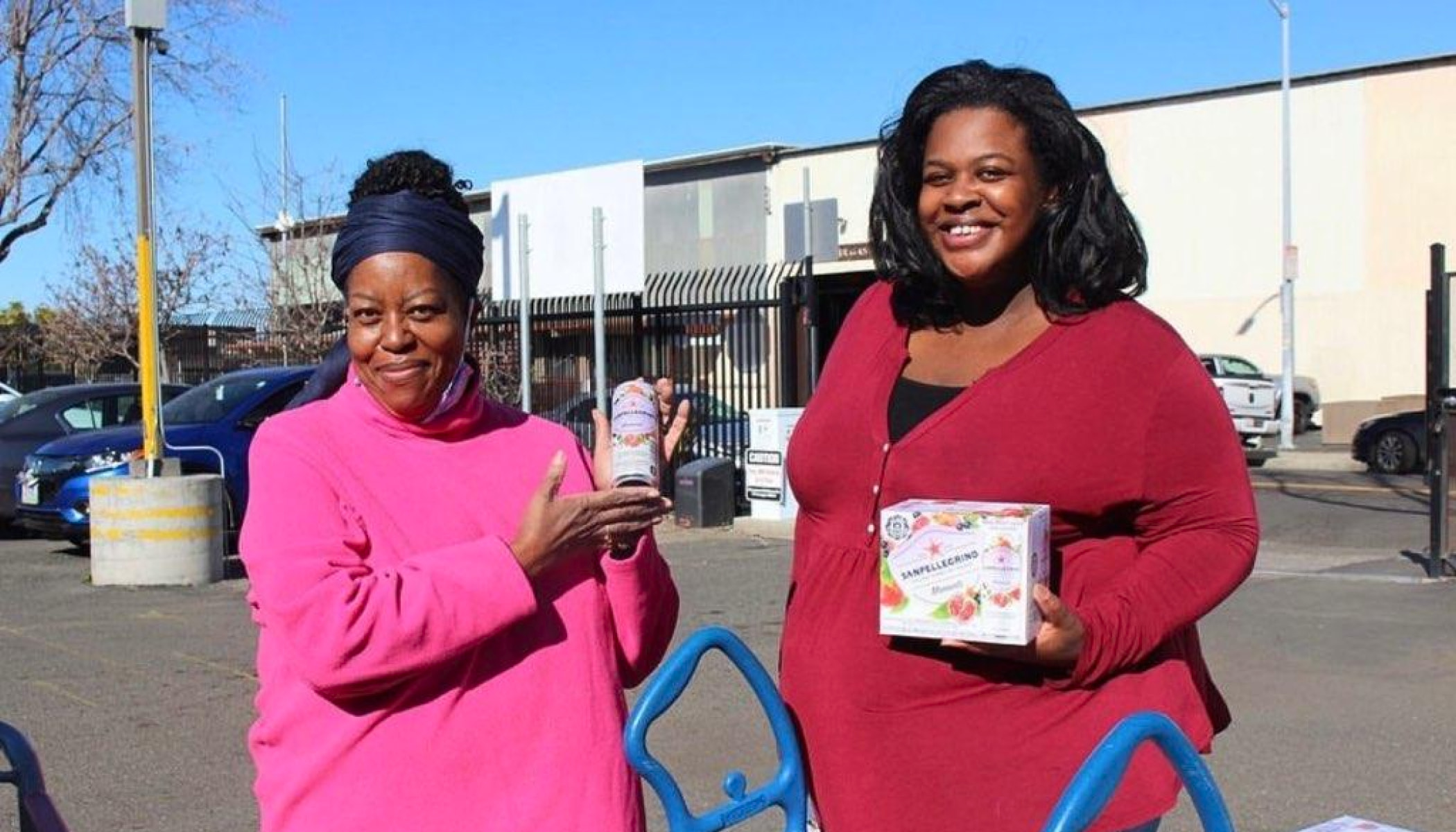 Two people, including LaKesha Roberts, smile for a photo while holding groceries.