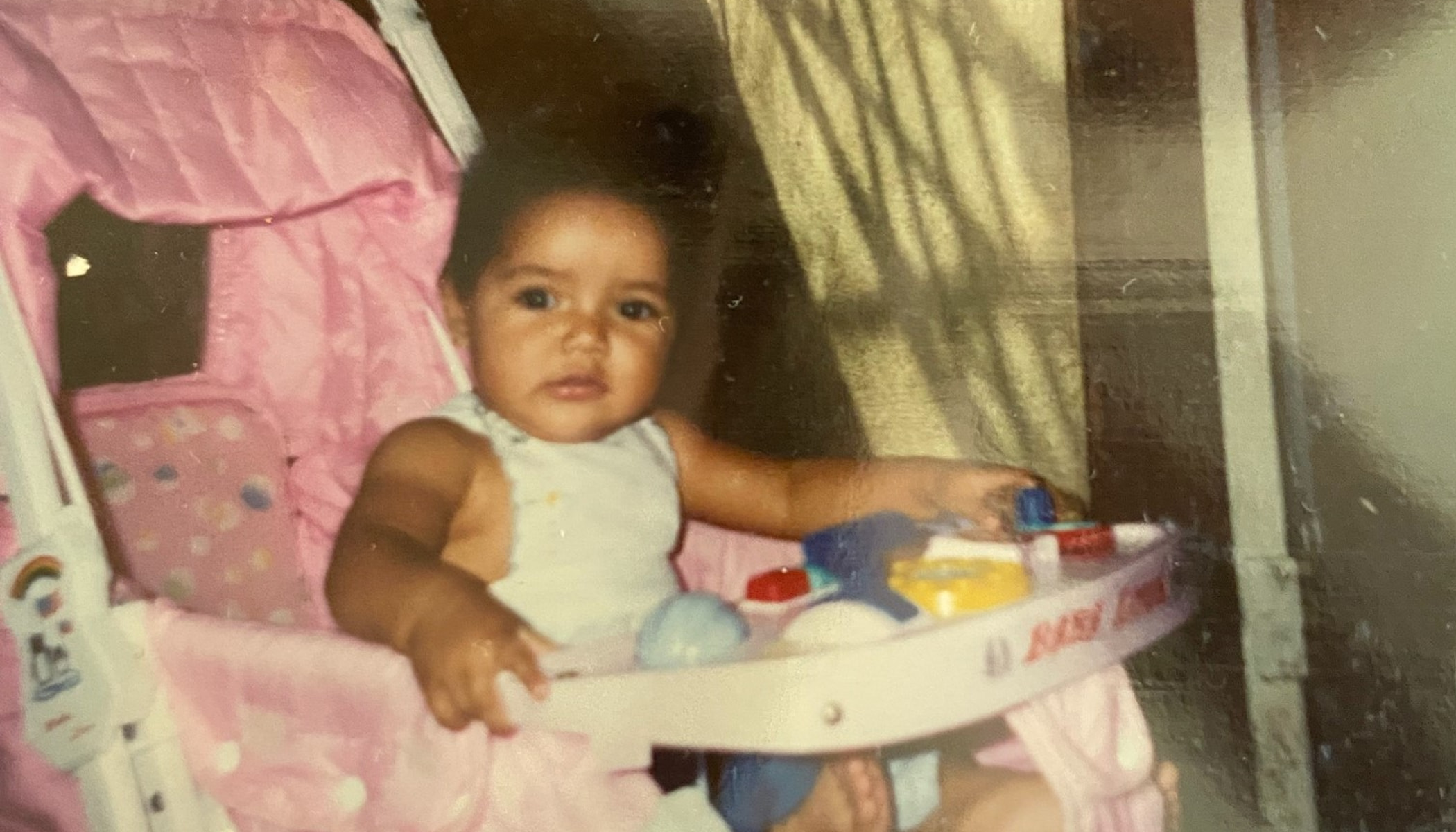 A young child sits in a pink stroller.