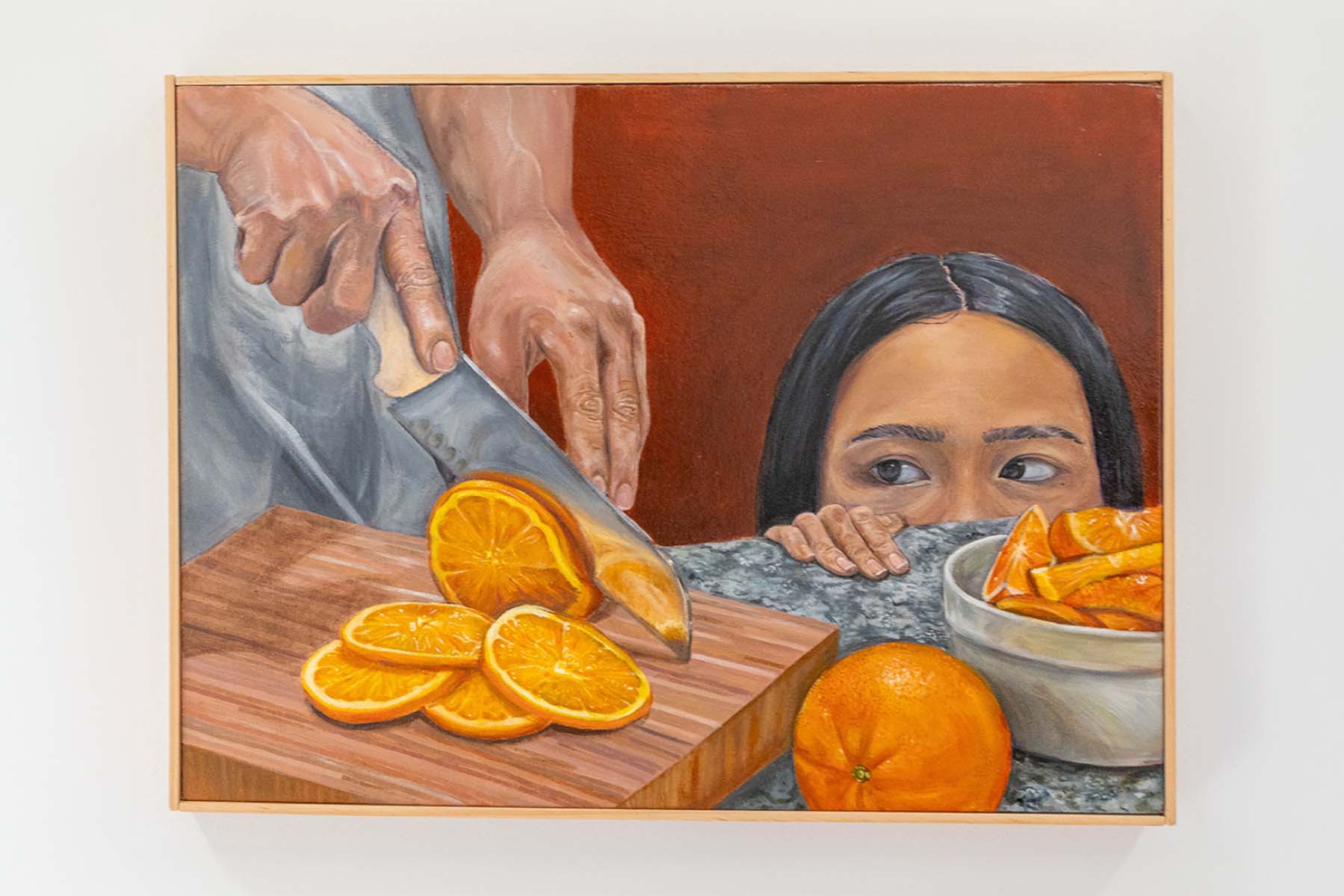 Child peering over counter to see oranges being sliced.