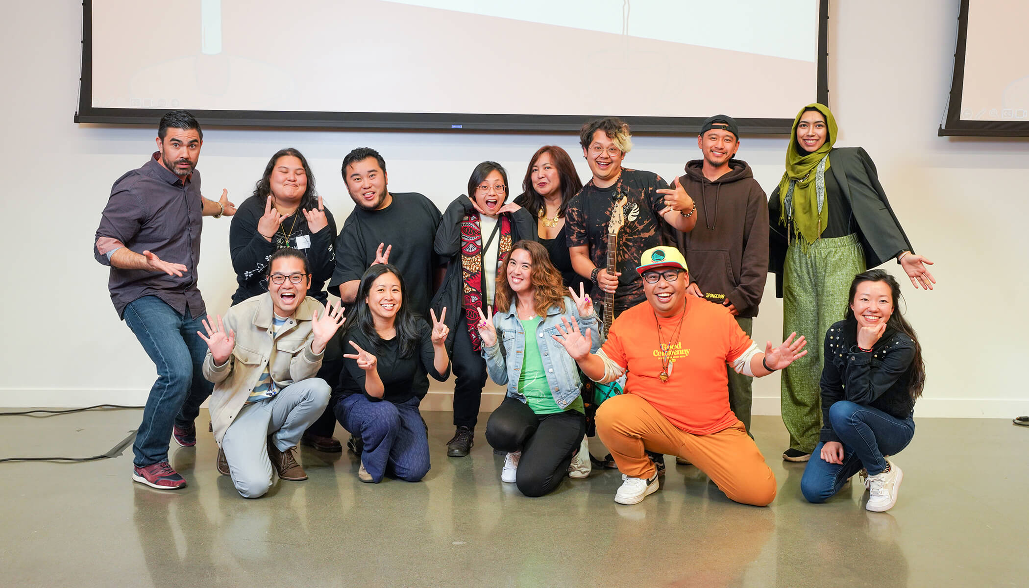 People pose for a picture, making various facial expressions and hand gestures.