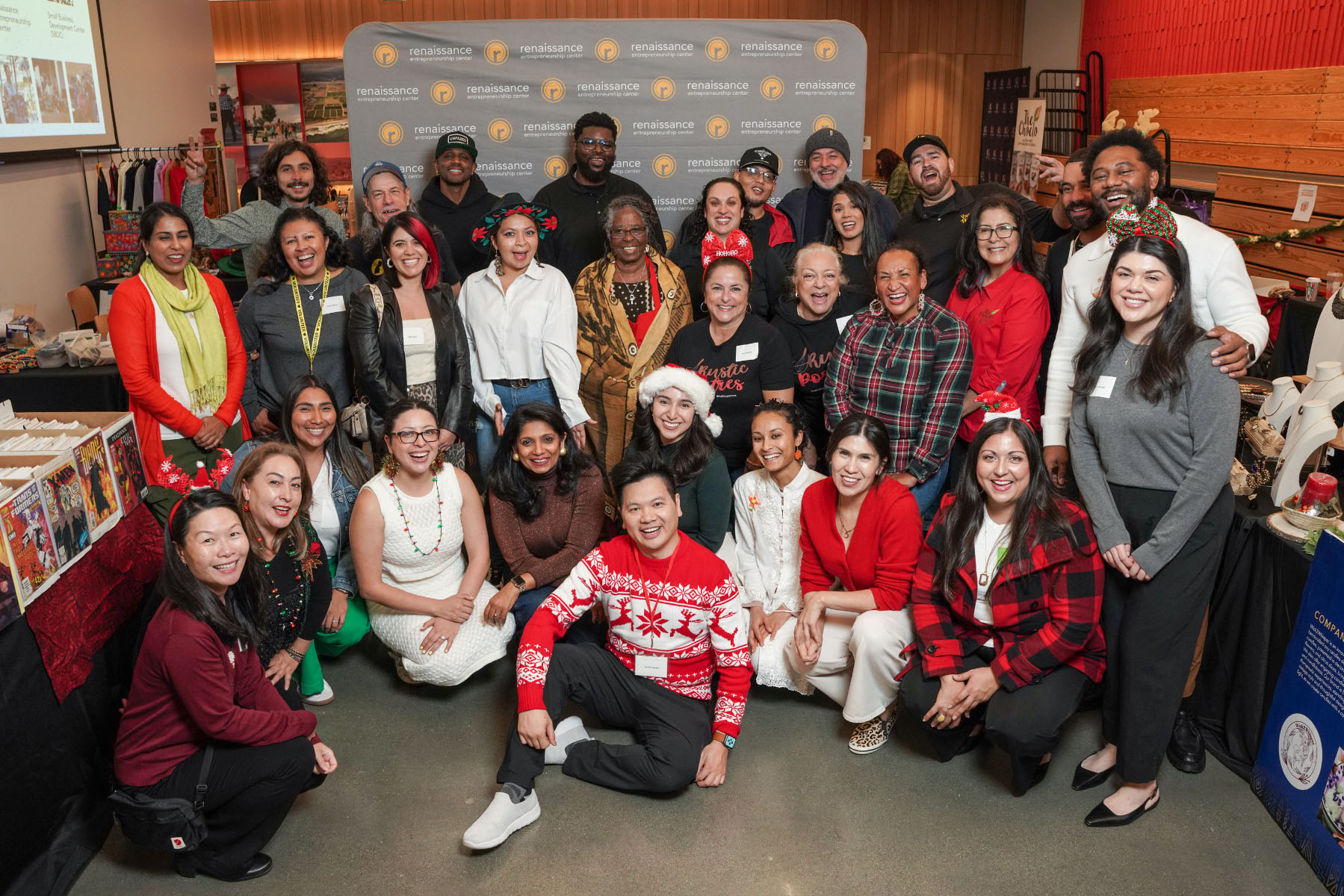 A group of people smile and pose in front of a backdrop that says, “Renaissance Entrepreneurship Center.”